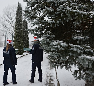 Policjanci w mikołajkowych czapkach na głowach niosą paczki