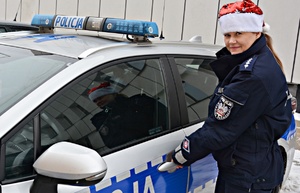 Policjantka w mikołajkowej czapce przy radiowozie