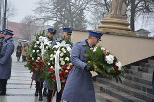 Policjanci z wieńcami kwiatów