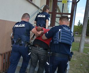 Policjanci prowadza mężczyznę skutego w kajdankach