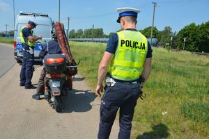 Dwóch policjantów kontrolujących osobę na motorowerze