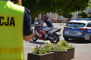 policjant na tle radiowozu i motocykla