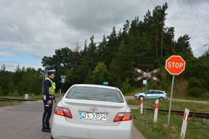 Policjant kontroluje pojazd przy przejeździe kolejowym