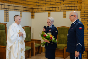 Policjanci z wręczają kwiaty dla księdza