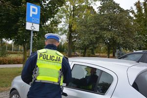 Policjant kontroluje parking dla osób niepełnosprawnych