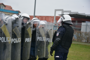 Policjanci w kaskach i tarczami na stadionie