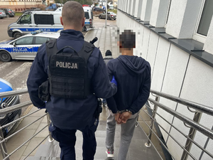 Policjant prowadzi zatrzymanego mężczyzną