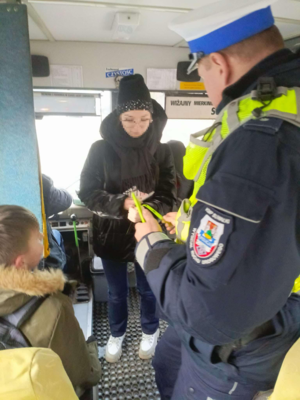 Policjant rozdaje odblaski w autobusie