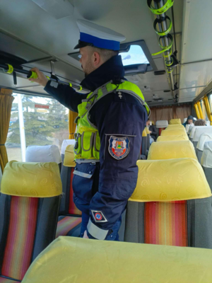 Policjant rozwiesza odblaski w autobusie