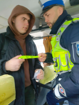 Policjant rozdaje odblaski w autobusie