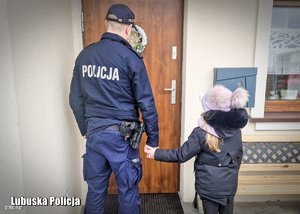 Policjant z dzieckiem przed domem