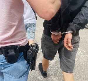 Policjant prowadzi skutego w kajdanki mężczyznę
