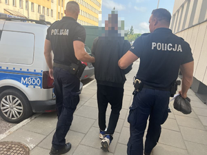 Policjanci prowadzą zatrzymanego mężczyznę