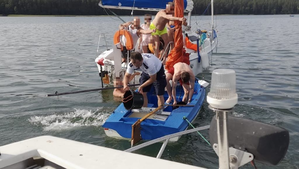 Żaglówka na jeziorze policjant wylewa wodę