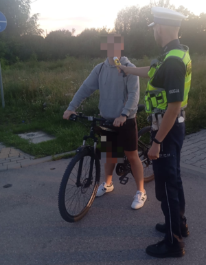 policjant sprawdza stan trzeźwości rowerzysty.
