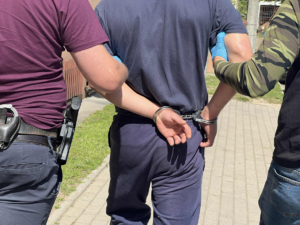 Policjanci prowadzą mężczyznę skutego w kajdanki