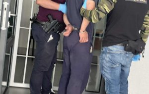 Policjanci prowadzą mężczyznę skutego w kajdanki