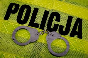 kajdanki na kamizelce odblaskowej z napisem policja