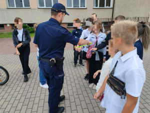 Policjant rozdaje odblaski dzieciom