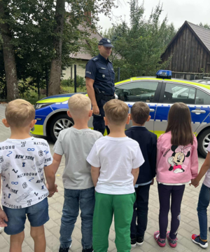 Policjant z dziećmi przy radiowozie