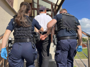 Policjanci prowadzą zatrzymanego mężczyznę