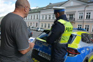 Policjant wręcza ulotkę mężczyźnie
