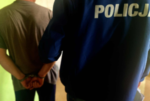 policjant z zatrzymanym mężczyzną w kajdanakach