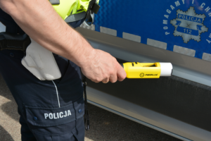 policjant z urządzeniem promiler przed radiowozem służbowym