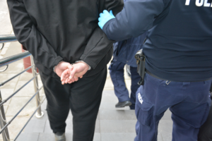 Policjanci prowadza zatrzymanego