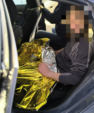 mężczyzna przykryty kocem termicznym w policyjnym radiowozie