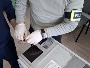 policyjny technik pobiera odciski palców od mężczyzny