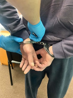 Policjant zakładający kajdanki zatrzymanemu