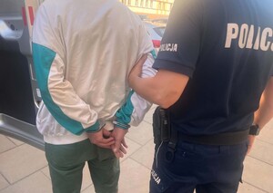Mężczyzna skuty w kajdanki prowadzony przez policjanta