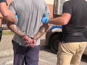 policjanci prowadzą mężczyznę skutego w kajdankach
